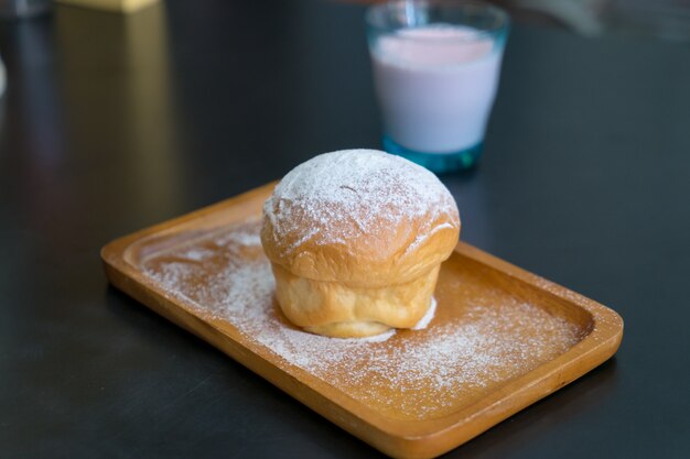 Pão de manteiga simples com pó de açúcar de confeiteiro na placa de madeira