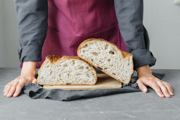 Pão de massa fermentada sem fermento, uma bela padeira europeia com pão nas mãos