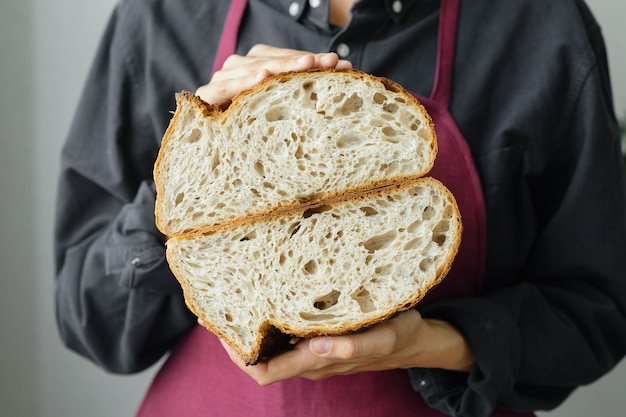 Pão de massa fermentada sem fermento, uma bela padeira europeia com pão nas mãos