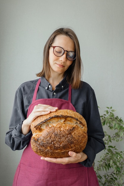 Pão de massa fermentada sem fermento, uma bela padeira europeia com pão nas mãos