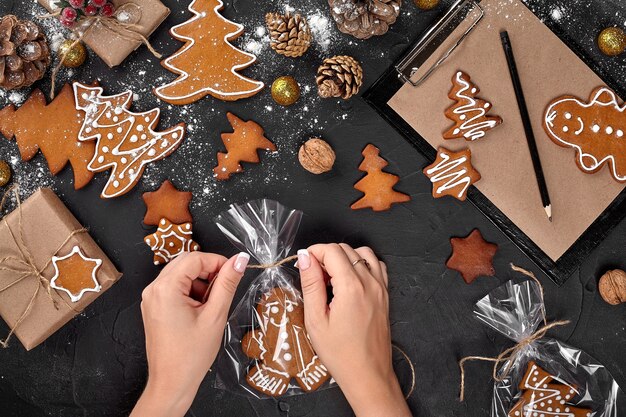 Pão de mel de presente de Natal em biscoitos de fundo escuro em uma embalagem festiva, a mulher é a embalagem de chris ...