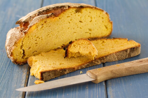 Pão de milho com faca em madeira azul