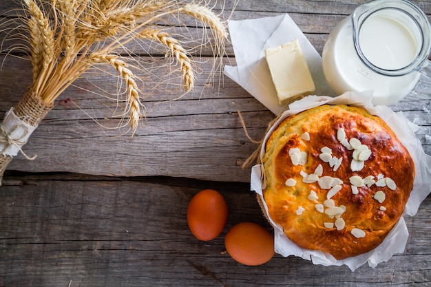 Pão de páscoa e ingredientes em fundo de madeira rústico