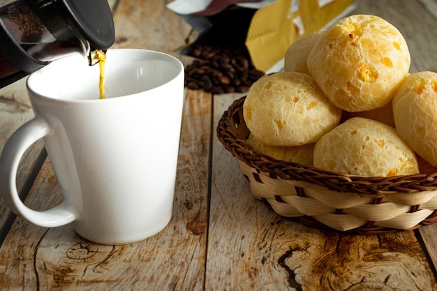 Pão de queijo brasileiro ou 'pao de queijo' e café em uma cesta de madeira e mesa de madeira