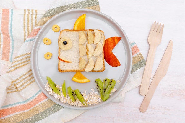 Pão de torrada de sanduíche de forma de peixe fofo engraçado com banana maçã laranja Crianças crianças sobremesa doce café da manhã saudável arte de comida de almoço no fundo de madeira close uptop view