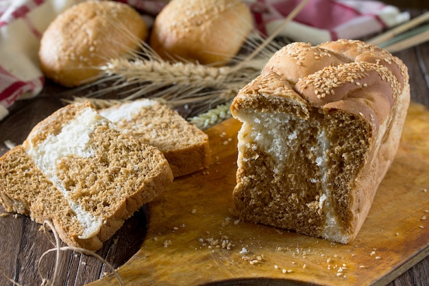 Pão delicioso com gergelim numa tábua de madeira