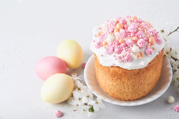 Pão doce de Páscoa tradicional ou bolos com glacê branco e decoração de açúcar ovos coloridos e galho de cerejeira sobre a mesa branca Vários bolos de Páscoa de primavera Feliz dia de Páscoa Foco seletivo