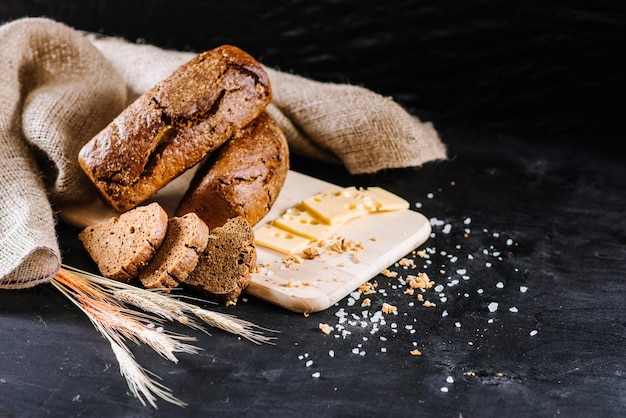 Pão doce e saboroso e trigo em fundo preto de madeira