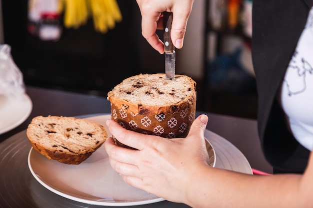 Pão doce tradicional para o Natal e o Ano Novo. - Close das mãos de uma cozinheira decorando o pão de Natal.