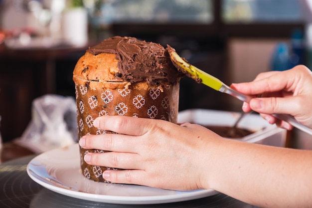 Foto pão doce tradicional para o natal e o ano novo. - close das mãos de uma cozinheira decorando o pão de natal.