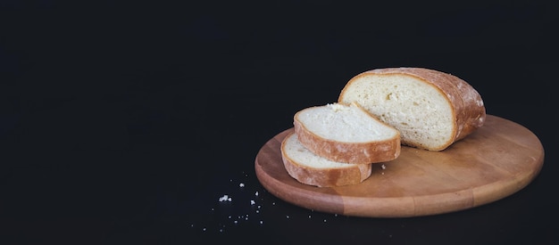 Foto pão e farinha em uma tábua de madeira cozimento caseiro