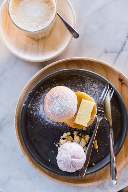 Pão e manteiga no topo com açúcar de confeiteiro servido com uma colher de sorvete de taro.