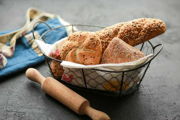 Pão em uma cesta em uma superfície preta. pão sortido em uma cesta de metal. lugar para receita e texto. asse o pão com um rolo e a farinha. pão de centeio, rolos de trigo sarraceno e baguete com sementes.