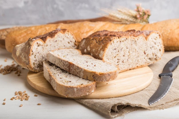 Pão fatiado com diferentes tipos de pão fresco sobre um fundo branco de madeira. vista lateral, close-up, foco seletivo.