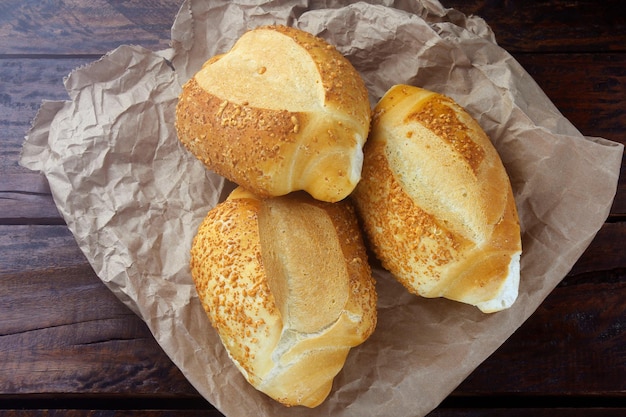 Pão francês brasileiro, em papel rústico, em mesa de madeira rústica para o café da manhã. gastronomia e brasil