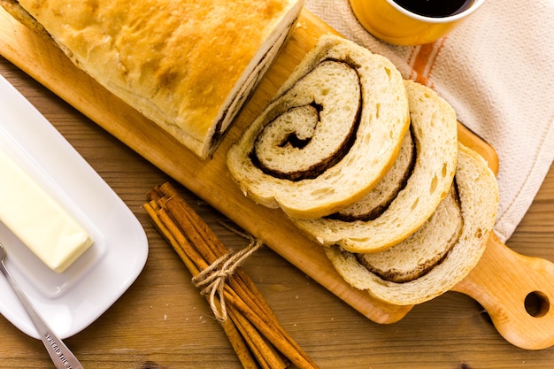 Pão fresco artesanal de redemoinho de canela fermento em cima da mesa.