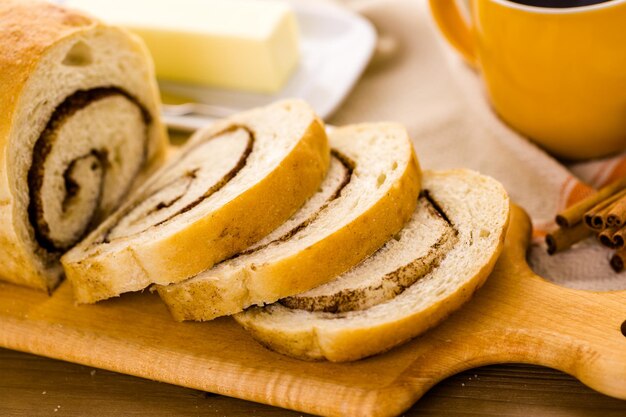 Pão fresco artesanal de redemoinho de canela fermento em cima da mesa.