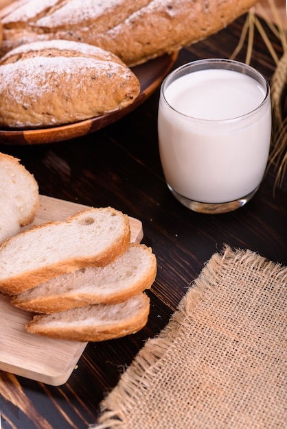 Pão fresco com leite na mesa de madeira preta.