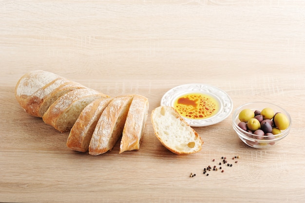 Pão fresco, cortado em fatias com azeitonas e azeite de oliva com vinagre balsâmico em uma tigela
