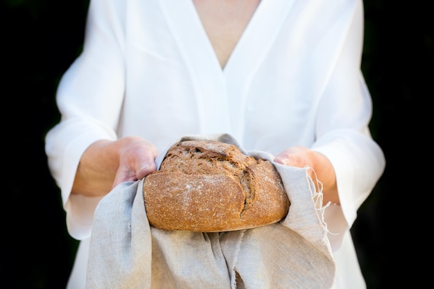 Pão fresco de pão de centeio caseiro nas mãos da mulher