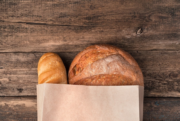 Pão fresco em um saco de papel em uma superfície de madeira