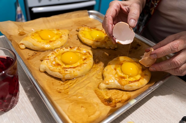 Pão georgiano tradicional khachapuri madjarski com mão de fogãoCozimento caseiro em cimaKhachapuri com queijo georgiano khachapuri megruli com queijo Processo de cozimento de torta georgiana tradicional