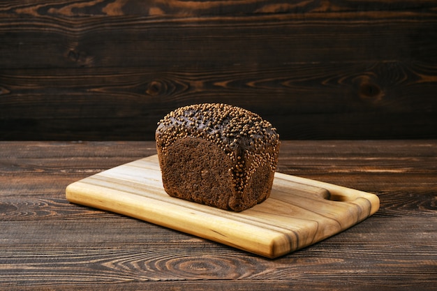 Pão integral de centeio fresco em uma tábua de madeira