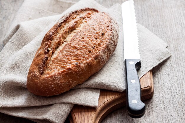 Pão integral de tábua de madeira na mesa da cozinha