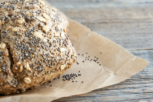 Foto pão integral, pão de centeio com sementes de girassol, flocos de chia e aveia em papel manteiga. fechar-se. lugar para texto