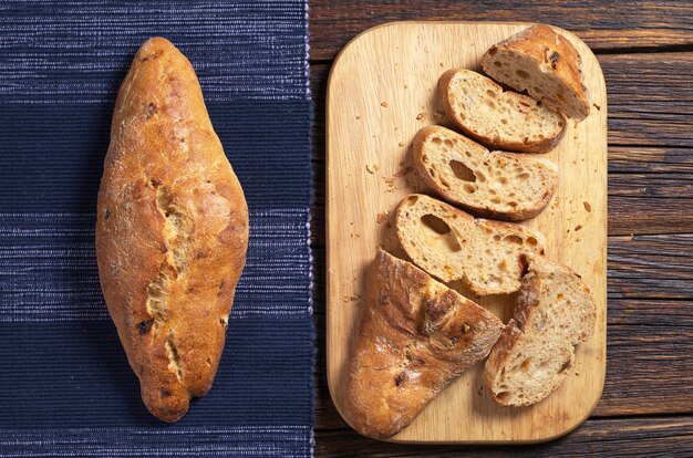 Foto pão italiano ciabatta inteiro e fatiado na mesa