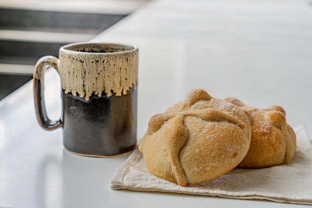 Pão mexicano tradicional dos mortos e xícara de café na mesa branca