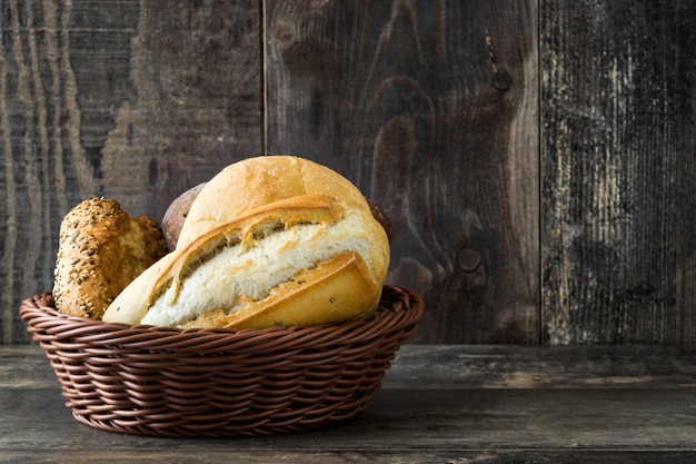 Pão misto na cesta na mesa de madeira