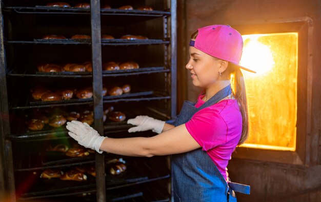 Pão nas mãos de um padeiro no fundo de um forno industrial. Produção de pão industrial