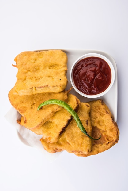 Pão Pakora ou pakoda servido com ketchup de tomate, verde frio e fatias de cebola, popular lanche indiano na hora do chá. Foco seletivo