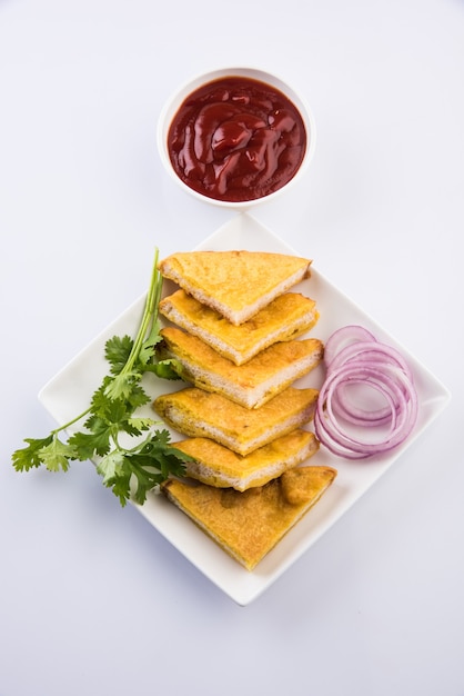 Pão Pakora ou pakoda servido com ketchup de tomate, verde frio e fatias de cebola, popular lanche indiano na hora do chá. Foco seletivo