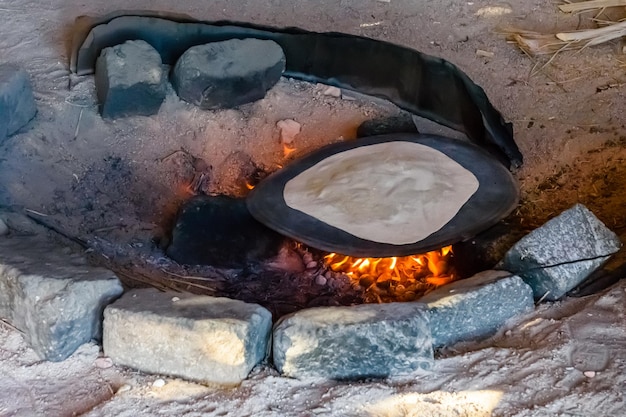 Pão pita cozinhando em chamas em uma habitação beduína