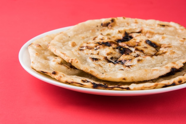 Pão plano especial indiano, também conhecido como tandoori roti de manteiga ou naan, servido em um prato de cerâmica branca