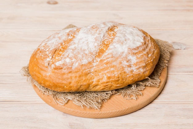 Pão recém-cozido na tábua de cortar contra fundo de madeira branca perspectiva de visão de pão com espaço de cópia