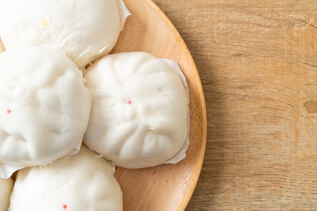 Pão recheado no vapor em prato de madeira - comida chinesa