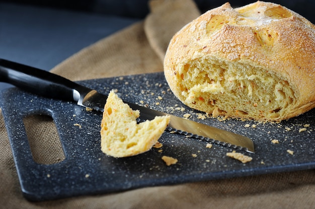 Pão redondo, uma faca de pão e um pedaço cortado