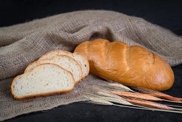 Pão saboroso doce e trigo em fundo de madeira