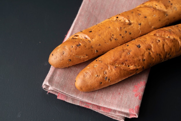 Pão saboroso fresco ou baguete na superfície preta na cozinha