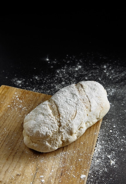 Pão sobre fundo preto farinha na mesa