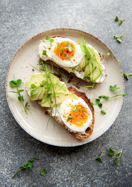 Pão torrada ovos cozidos abacate fatia microgreens em um prato