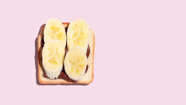 Pão torrado com banana e chocolate no fundo rosa