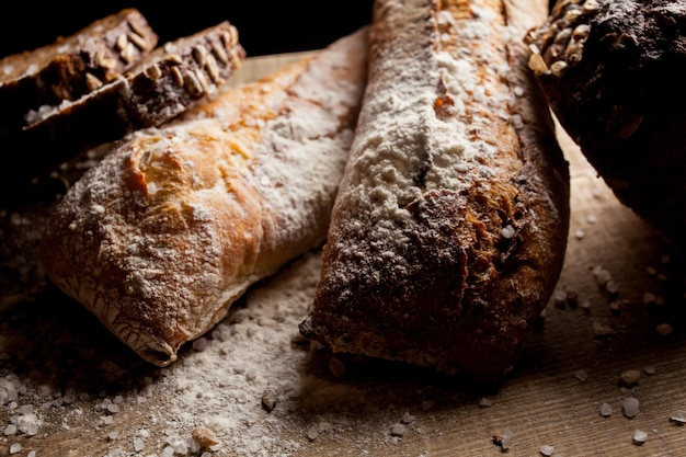 Pão tradicional recém-assado com farinha na mesa de madeira baguete fresca com farinha