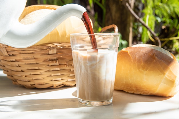 Pão, uma panela servindo café em um copo de leite americano