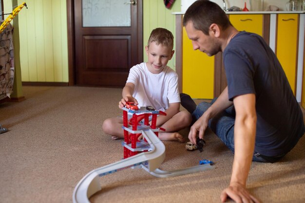 Papá alegre juega con un chico lindo en casa en autos