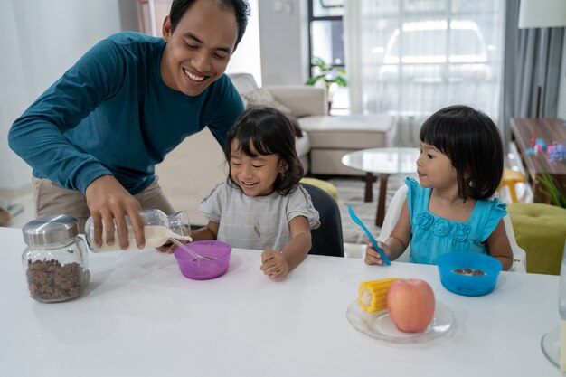 Papá asiático desayunando con sus dos hijas