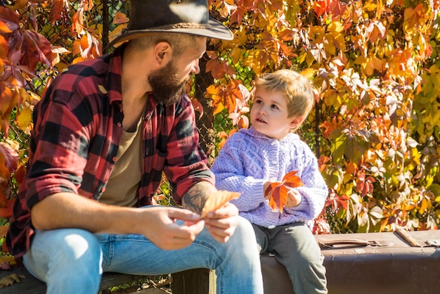 Papá barbudo diciéndole a su hijo sobre viajes. Viajero con mucha experiencia. Paternidad y crianza. Tiempo familiar. Aventura con hijo. Contar historias de tiempos pasados. Padre con maleta y su hijo